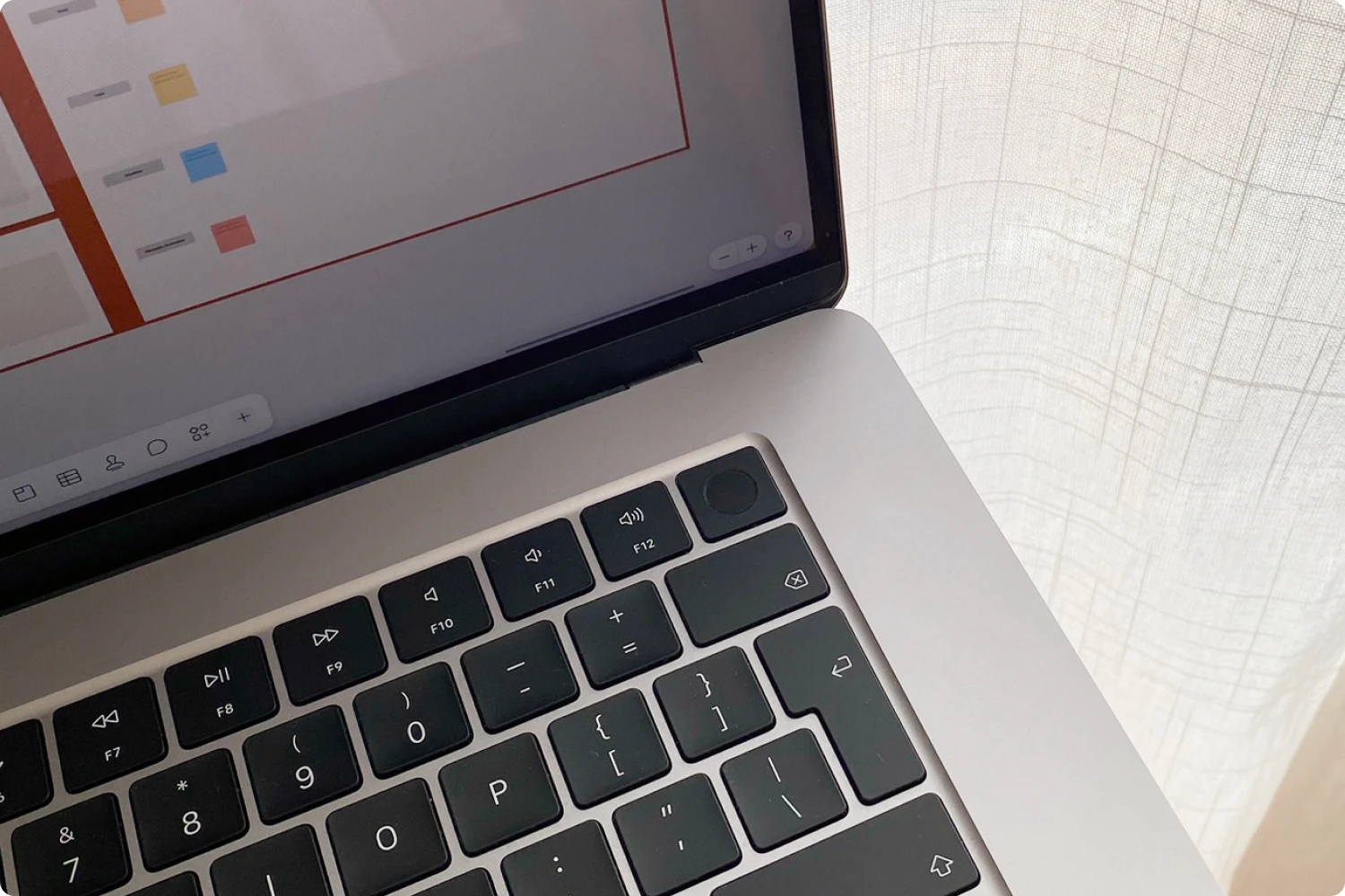 Close-up of a laptop with a presentation slide on the screen. Soft natural light is filtering through a curtain.